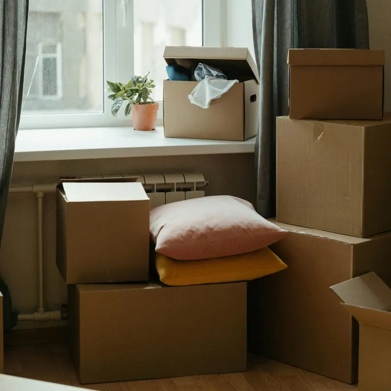 Umzugskartons die neben einem Fenster gestapelt sind